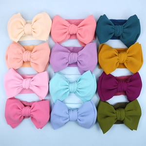 Flat lay of 12 colorful waffle knit baby headbands with large bows in a 3x4 grid display