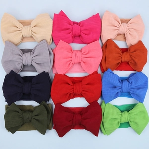 Flat lay of 12 colorful textured nylon baby headbands with large bows in varied shades