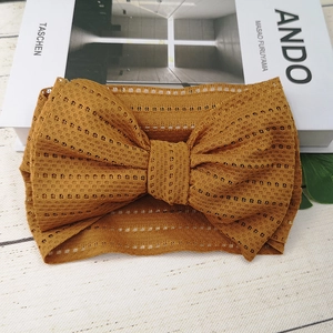 Detail eines senfgelben Spitzenstirnbands mit weicher Strickschleife auf hellem Hintergrund