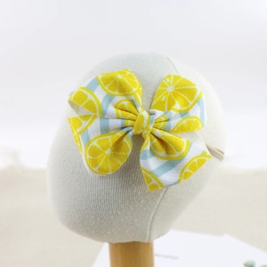 Elastic baby headband with a large lemon print bow on a white mannequin head