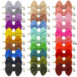 Close-up of thirty colorful bow headbands with waffle texture on soft nylon elastic bands