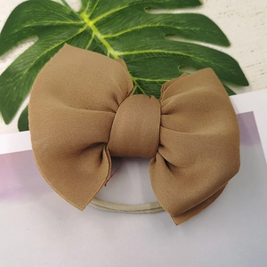 Detail of a brown ribbed fabric double layer bow on a grey elastic headband
