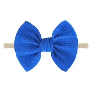 Detail of baby headband featuring textured dark blue bow on soft nylon elastic band