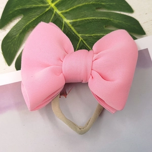 Pink 3D puffy bow headband for infants with elastic seamless band on monstera leaf background