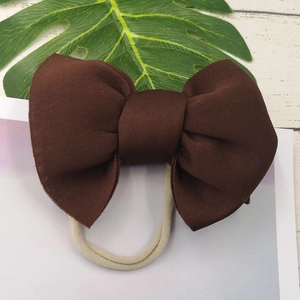 Close-up of baby headband featuring a coffee brown puffed bow with cream nylon elastic strap