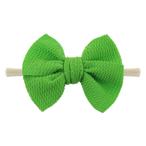 Detailed view of bright green waffle fabric bow on a soft nude nylon baby headband