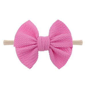 Detail of bright pink waffle weave bow on a soft stretch nylon headband for babies