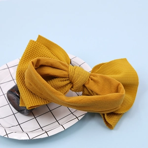 Detail of ginger yellow knitted nylon headband with a large bow showing soft texture