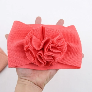 Détail d'un bandeau pour bébé rouge corail en tissu gaufre avec décoration florale