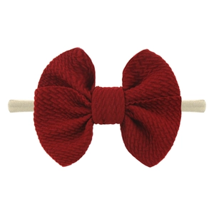 Close-up of dark red nylon bow headband for babies with textured ribbed fabric