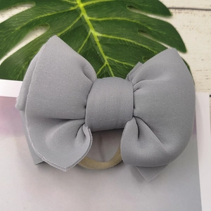 Detailed view of the layered grey fabric bow hairband with a high-elastic nude head loop
