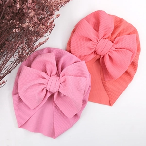 Detail view of pink bubble fabric baby turban hats with large bows on white background