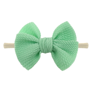 Macro detail of mint green waffle fabric bow on high-elastic nylon baby headband