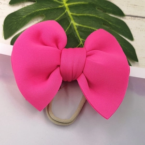 Detail of rose pink large bow headband with textured elastic knit fabric for infants