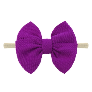 Detail of a purple textured bow headband with high-elastic nylon band for infants