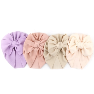 Detailed waffle texture of four colorful baby turbans with large decorative bows