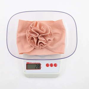 Détail d'un bandeau pour bébé rose à texture gaufrée avec une grande fleur sur balance