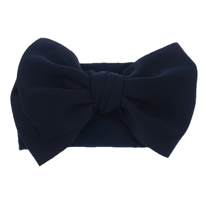 Detail of navy blue nylon baby headband featuring a large elastic knitted bow design