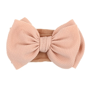 Detail showing soft ribbed texture and bow design of the baby pink nylon headband