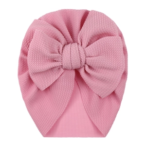 Close-up of pink waffle fabric texture and large bow on this baby turban hat