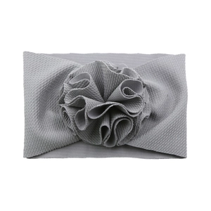 Détail d'un bandeau pour bébé gris clair en maille gaufrée avec une grande fleur décorative