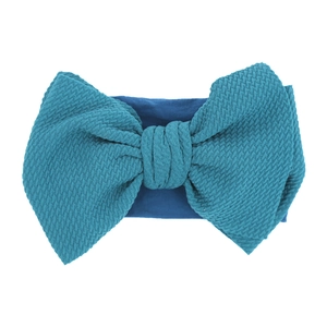 Detail of teal waffle knit baby headband featuring a large soft textured bow design
