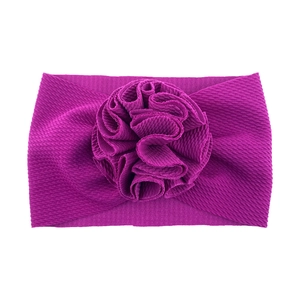 Détail du bandeau bébé magenta en maille gaufrée avec une grande fleur faite à la main