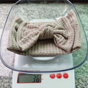 Détail montrant le poids de 36g du bandeau bébé en maille gaufrette avec nœud sur balance