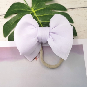 Detailed close-up of a large purple fabric bow headband with soft elastic nylon band