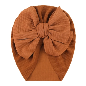 Detailed texture of caramel waffle fabric baby turban hat with large decorative bow