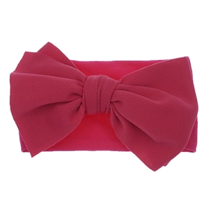 Detail of rose red nylon baby headband featuring a large textured ribbed knit bow
