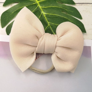 Detail of a beige puffed bow headband for babies made of soft elastic jersey fabric