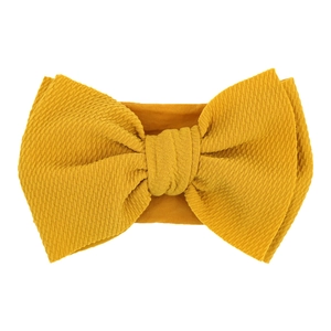 Close-up of ginger yellow waffle knit fabric baby headband with a large elastic bow