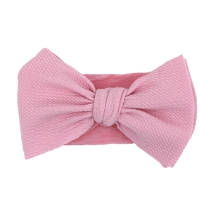 Close-up of pink bow headband for babies made of soft textured waffle knit fabric