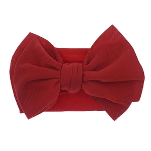 Detail of a dark red nylon baby headband with a large textured fabric bow