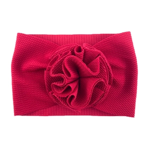 Détail du bandeau élastique rouge pour bébé avec grande fleur en tissu plissé sur fond blanc
