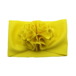 Détail d'un bandeau élastique jaune pour bébé orné d'une fleur en tissu gaufré texturé