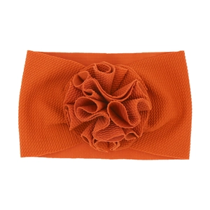 Gros plan du bandeau en maille gaufrée orange avec une décoration florale 3D détaillée
