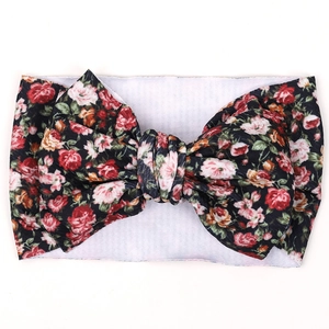 Detail of baby headband with oversized floral bow in vibrant red and orange colors