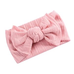 Detail der rosa gerippten Strickstruktur und gekreuzten Schleife am Baby Stirnband