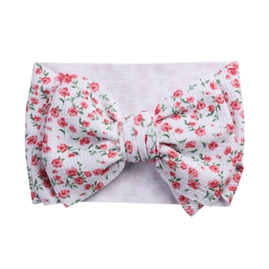 Detailed texture of white floral baby headband with a large handmade bow decoration