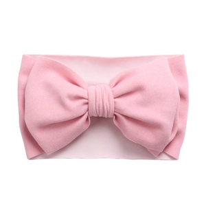 Détail du bandeau bébé rose souple et élastique avec un grand nœud en tissu superposé