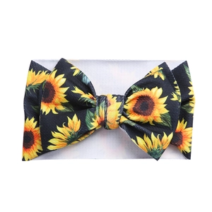Detail of baby headband featuring high-elastic white band and oversized sunflower bow