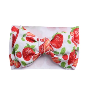 Close-up of white baby headband with red strawberry prints and large bow detail