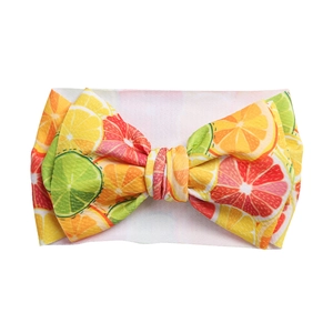 Detail of baby headband featuring vibrant citrus fruit print and large bow knot decoration