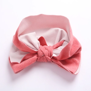 Détail d'un bandeau pour bébé rose corail doux avec un grand nœud en faux cachemire