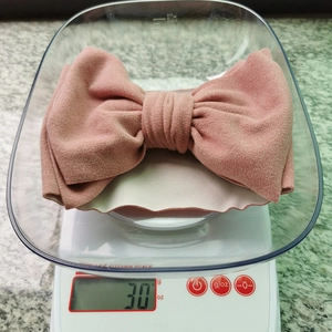 Gros plan d'un bandeau rose à nœud sur une balance indiquant un poids de 30 grammes