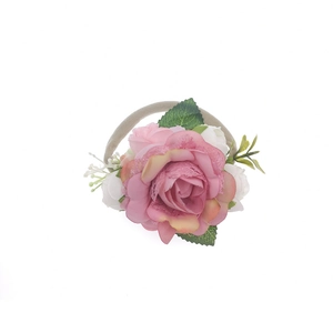Dettaglio di una fascia per neonati con rosa in tessuto rosa e piccoli frutti verdi