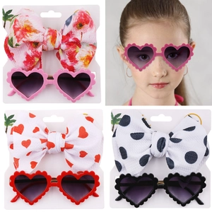 Close-up of heart-shaped sunglasses and matching floral bow headband for toddlers