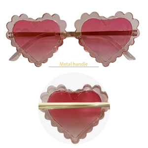 Detail of pink heart sunglasses with scalloped edges and gold metal temple hinges